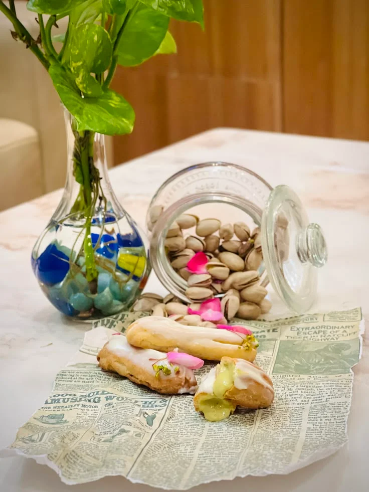 Glazed pastries with pistachio filling, rose petals, and a jar of pistachios